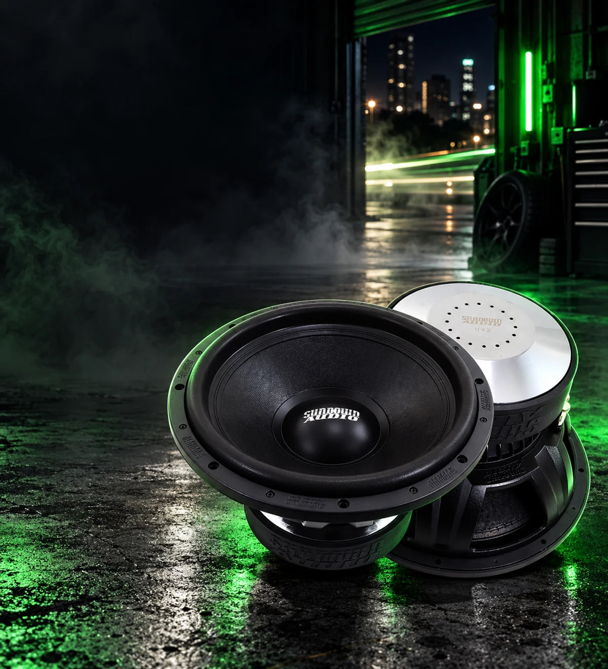Sundown Audio U-Series subwoofers on a wet garage floor under green light. Turn it up, build it right. Shop subwoofers at Car Audio Bargain.