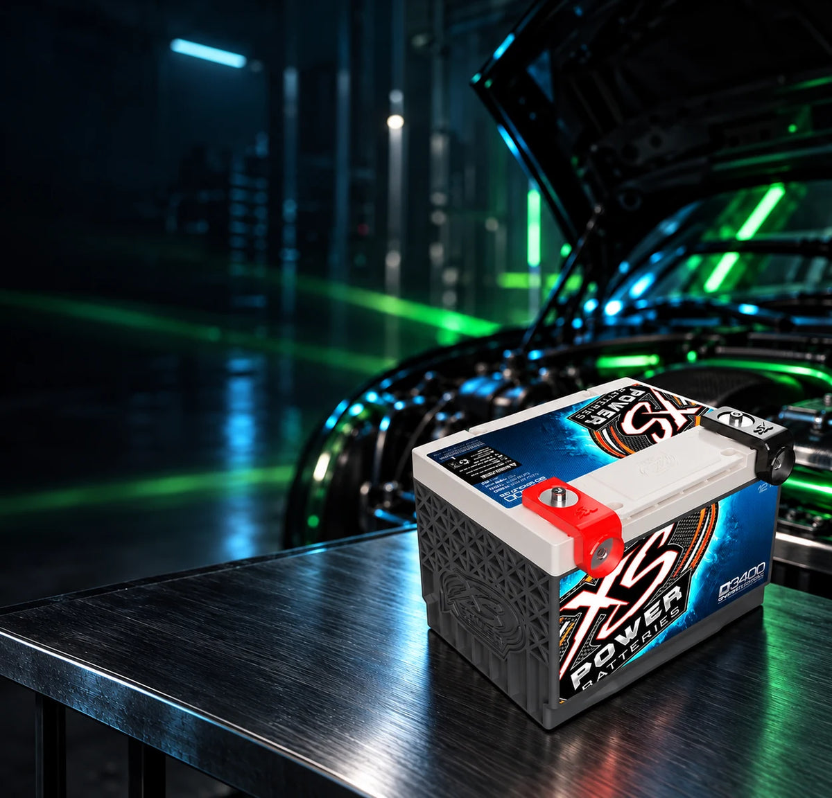 XS Power D3400 battery on a steel bench in front of an open engine bay. Feed your system. Shop batteries and power.